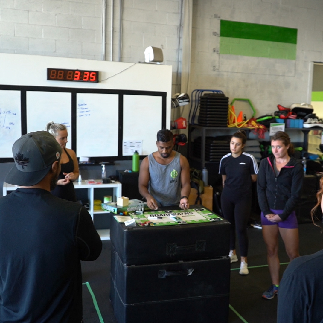 Fitness trainer standing in front of a group fitness class, explaining the workout routine and providing instructions to the participants