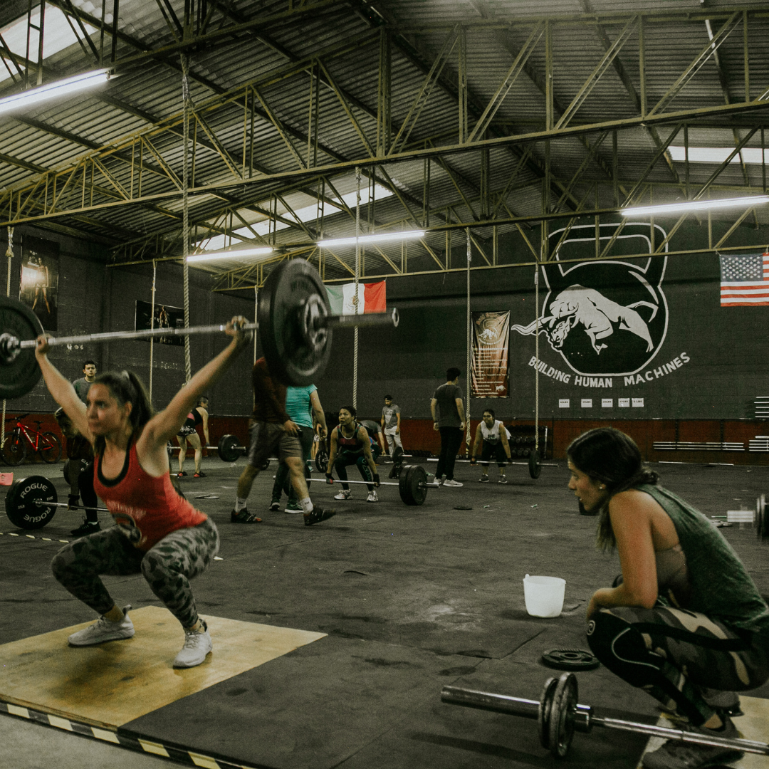 Group of athletes participating in a CrossFit class, engaged in intense physical activity to improve fitness and overall health