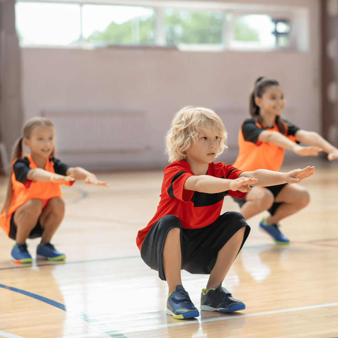 Kids' fitness strength training session, with children performing bodyweight squats to improve lower body strength and overall fitness